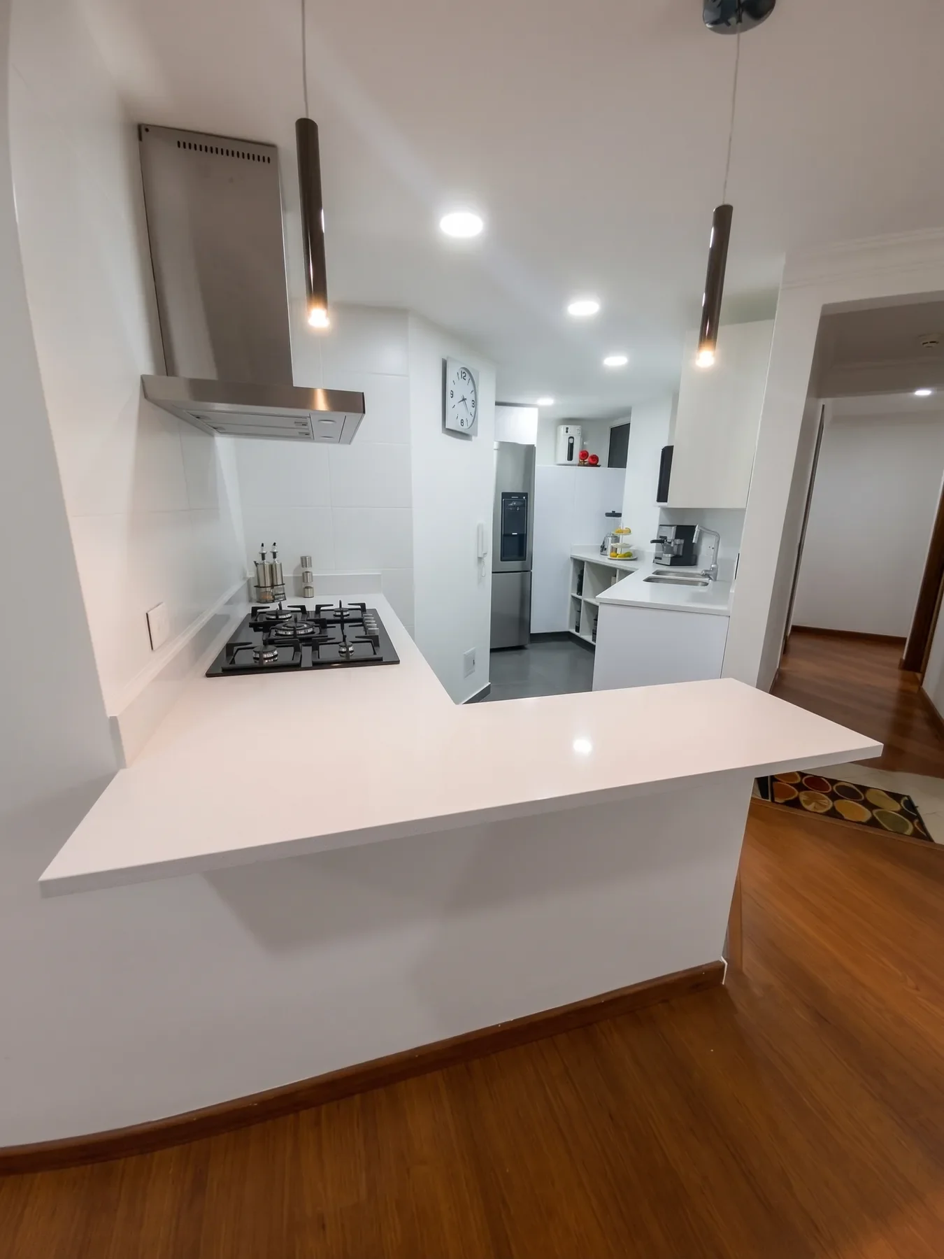 Cocina Arcos de Santa Bárbara remodelada: cocina blanca en L con mesón de cuarzo y campana de acero