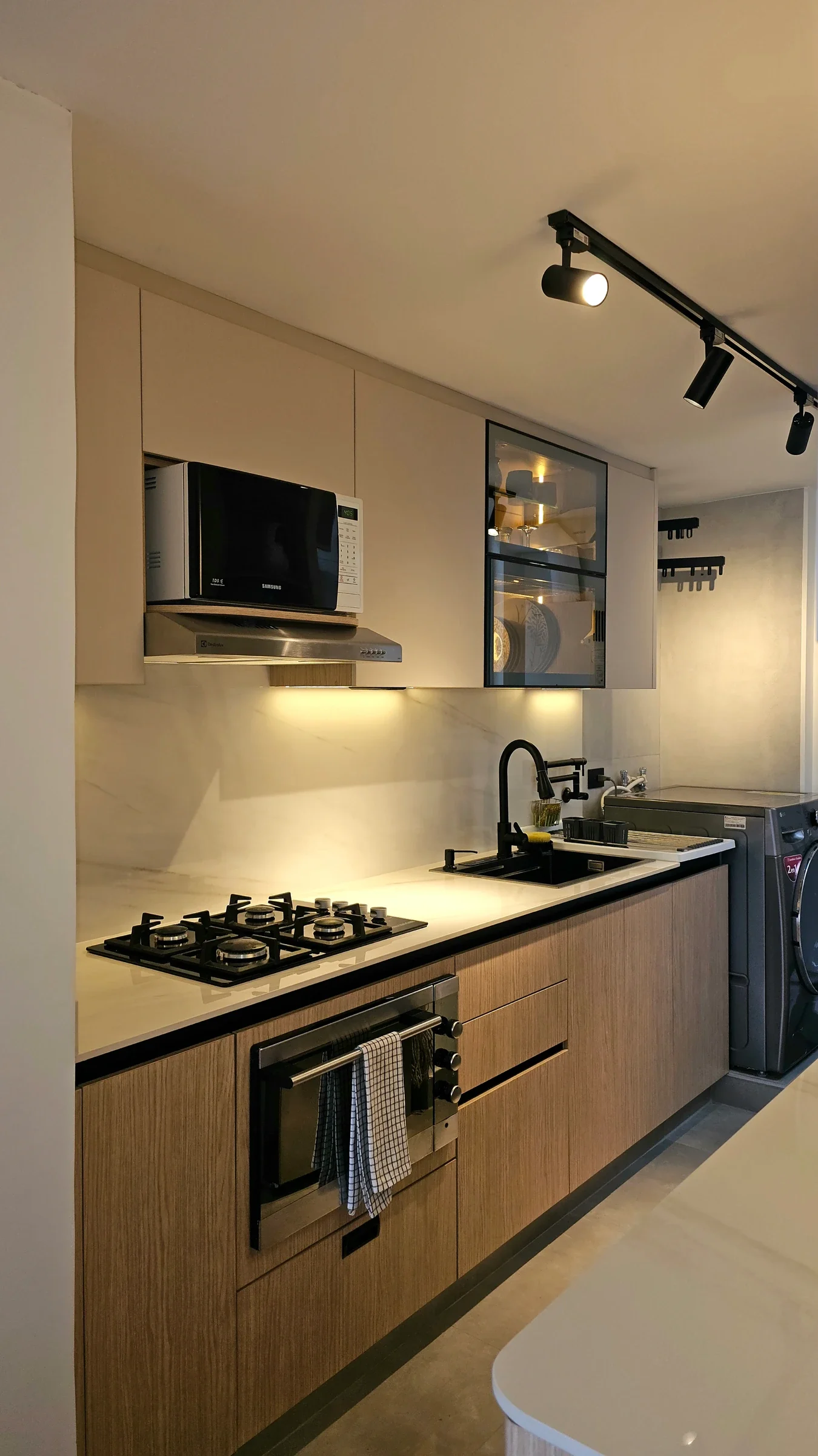 Cocina remodelada con gabinetes claros, riel de luz y horno empotrado