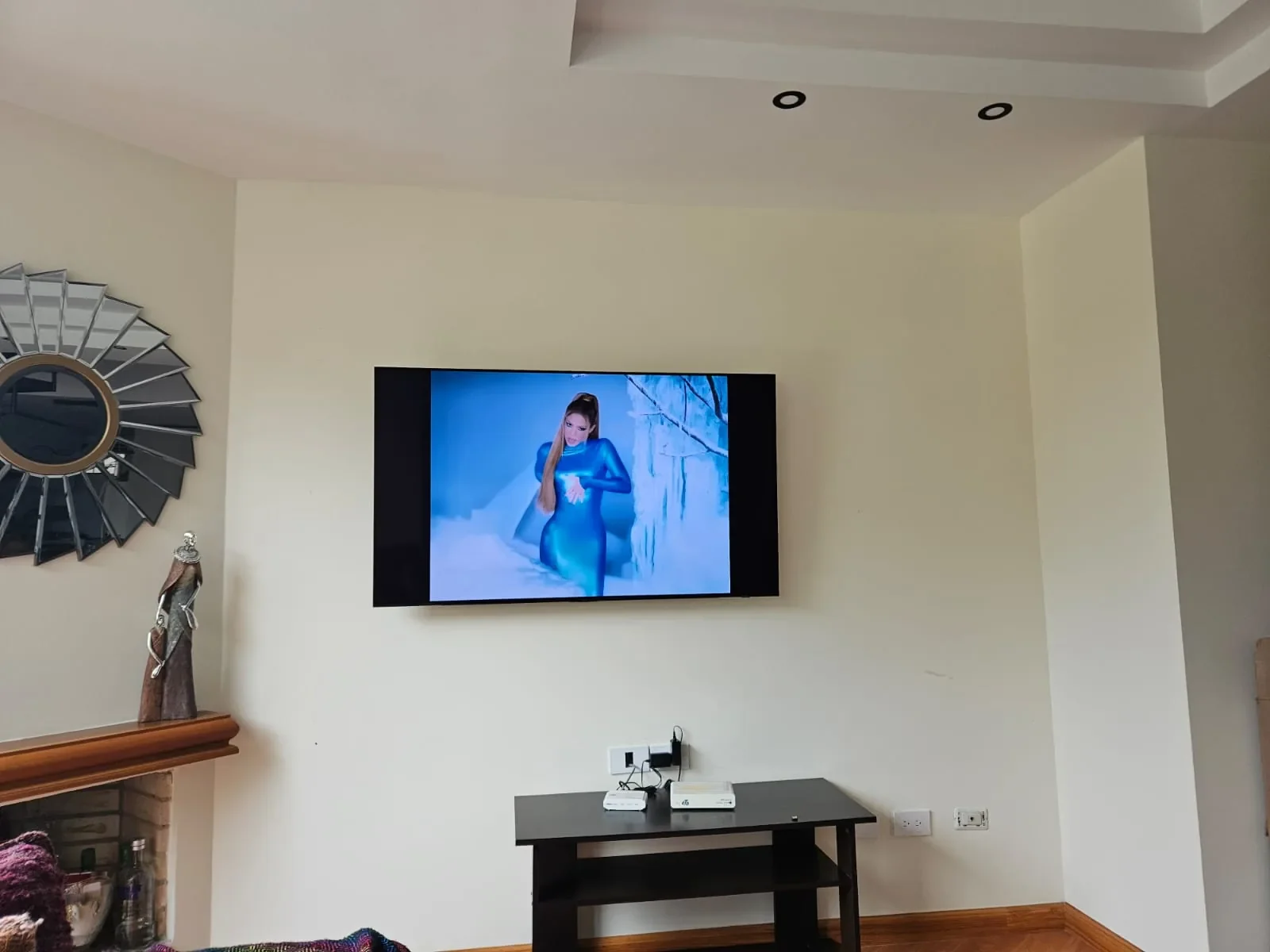 Sala antes: televisor colgado en una pared vacía sobre una mesa pequeña
