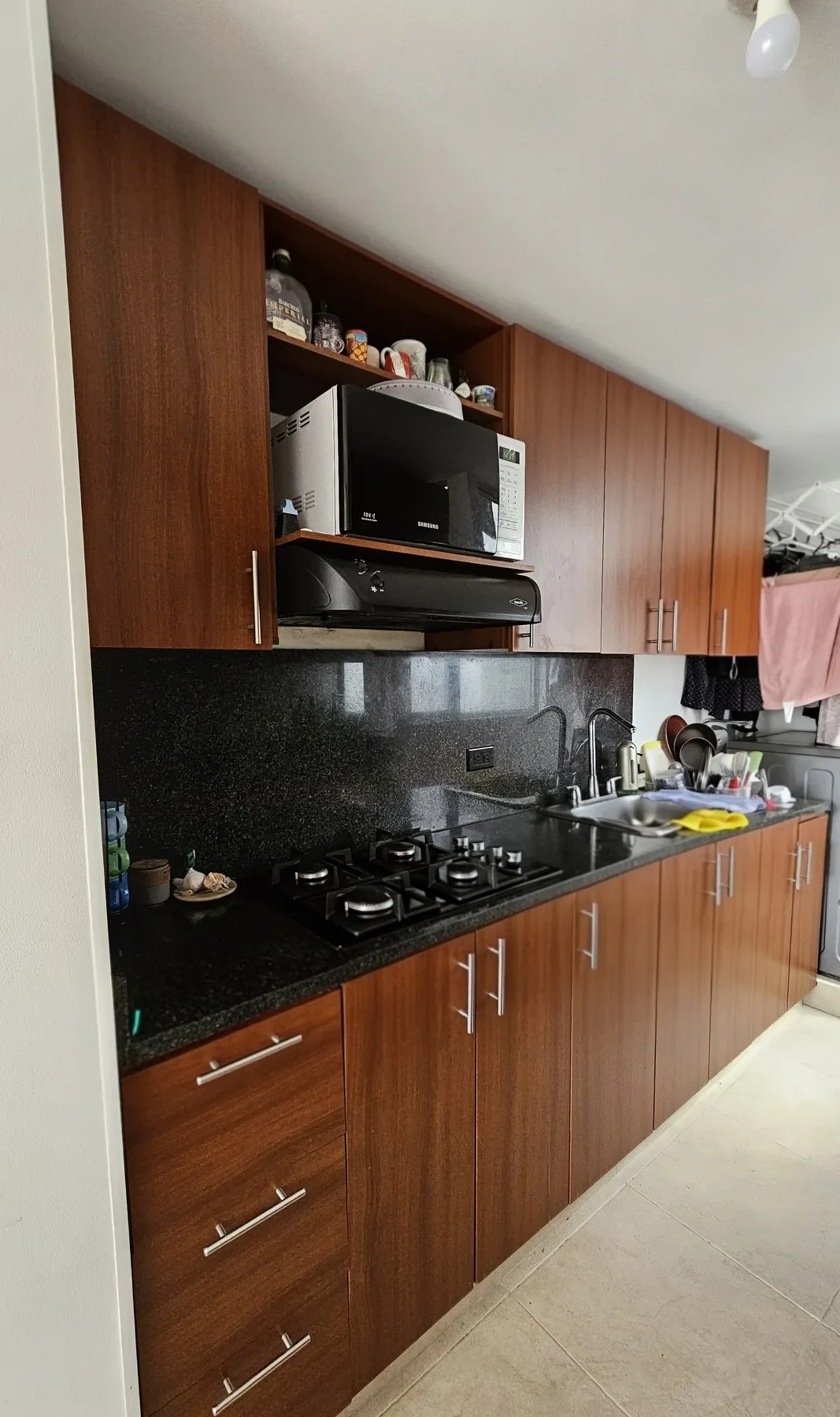 Cocina San Carlos antes: gabinetes de madera rojiza y mesón de granito negro